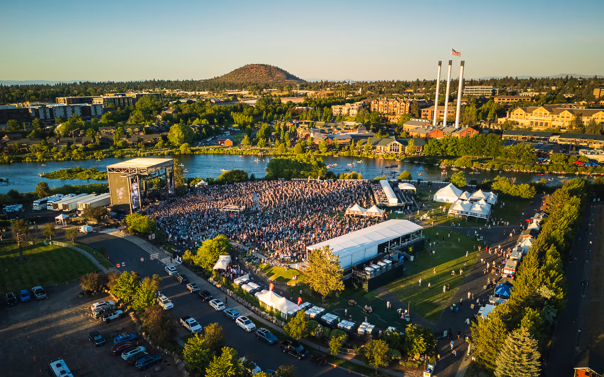 Aerial view of Hayden Homes Amphitheater in Bend, Oregon with the Deschutes River, Old Mill District stacks, and Pilot Butte in the background.