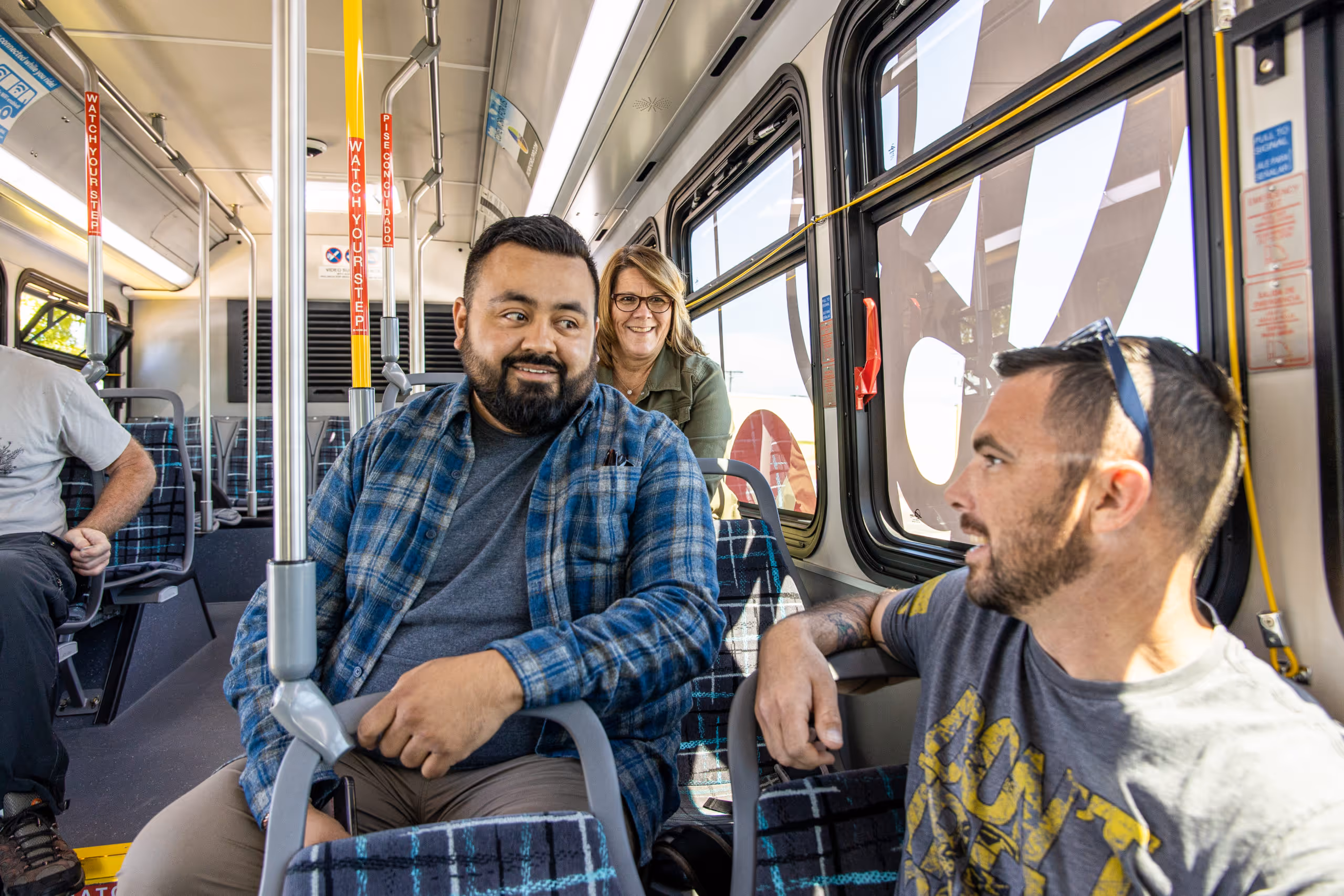 Two men and a woman smiling while chatting riding public transportation in Bend, Oregon.