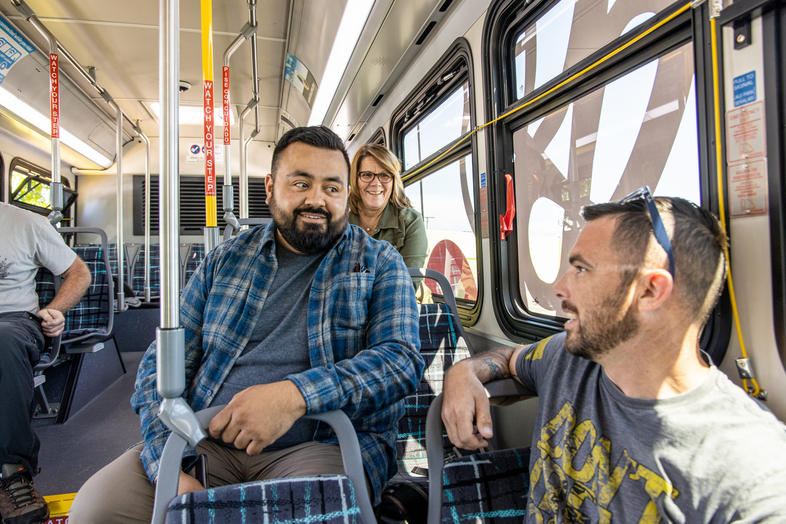 Two men and a woman smiling while chatting riding public transportation in Bend, Oregon.