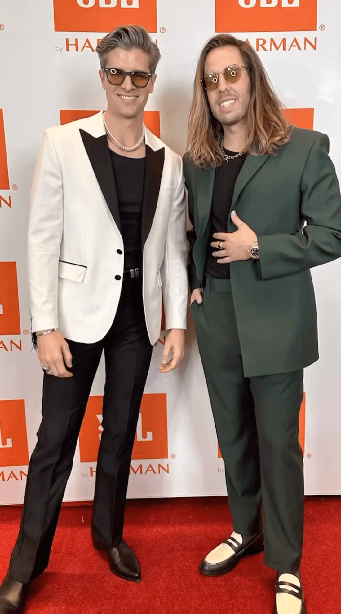 Two stylish men in fashionable suits posing confidently on the red carpet