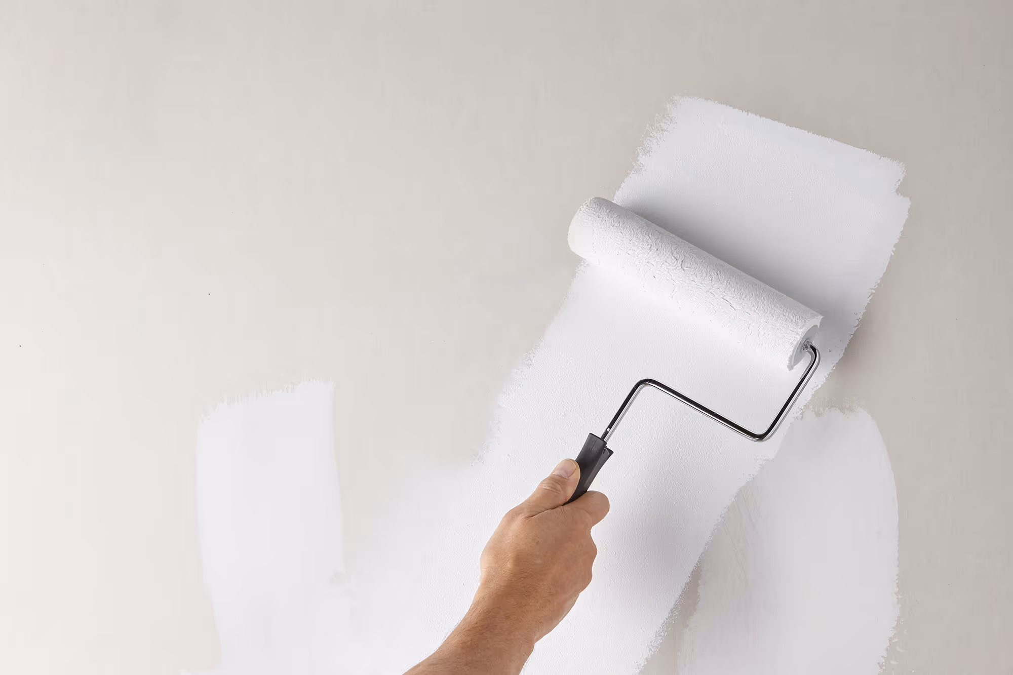 Painter cutting in and priming an interior wall