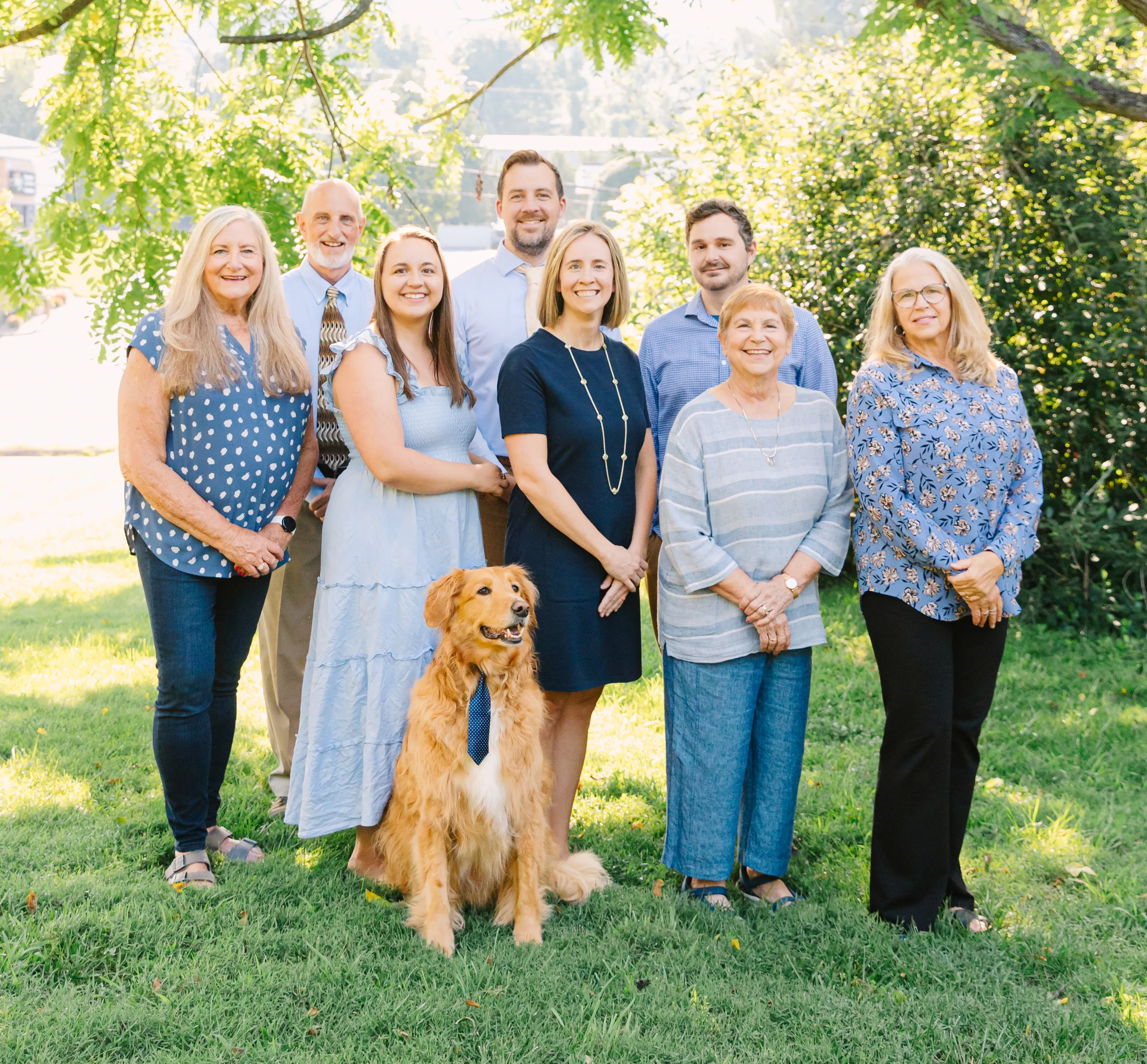 A group photo of JVG's staff, including Rocky, in a sunny outdoor setting.