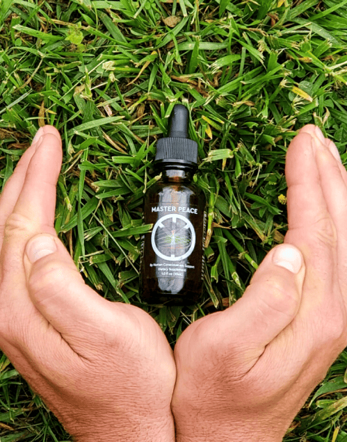 MasterPeace bottle held in cupped hands over green grass