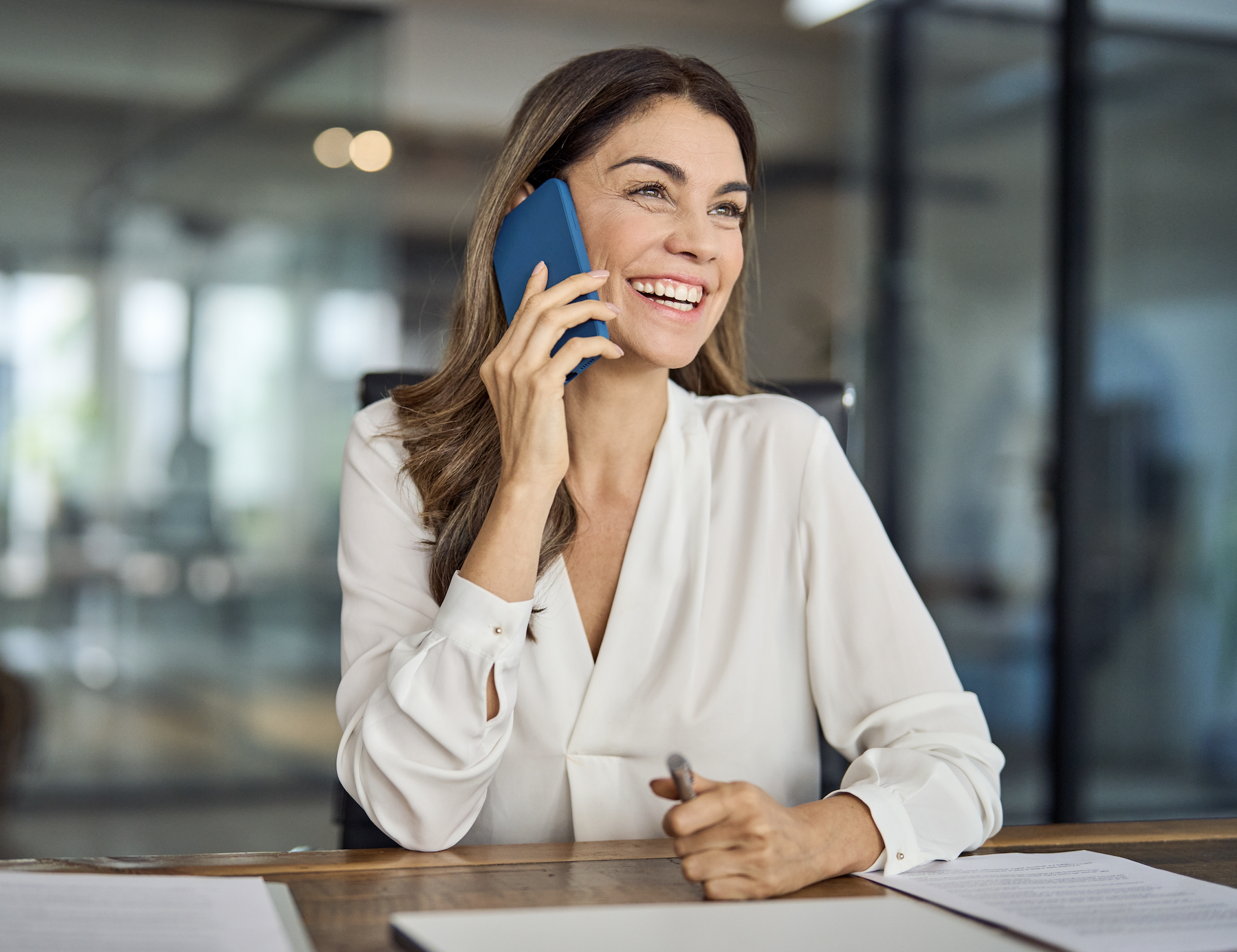 eine Frau die lacht und während dessen telefoniert.