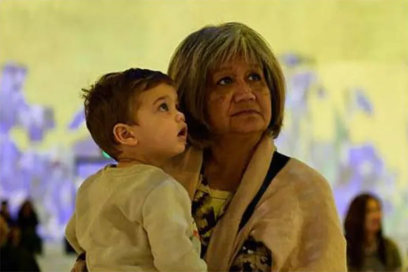 Older woman holding a young boy, both looking intently upward with an abstract blurred background.