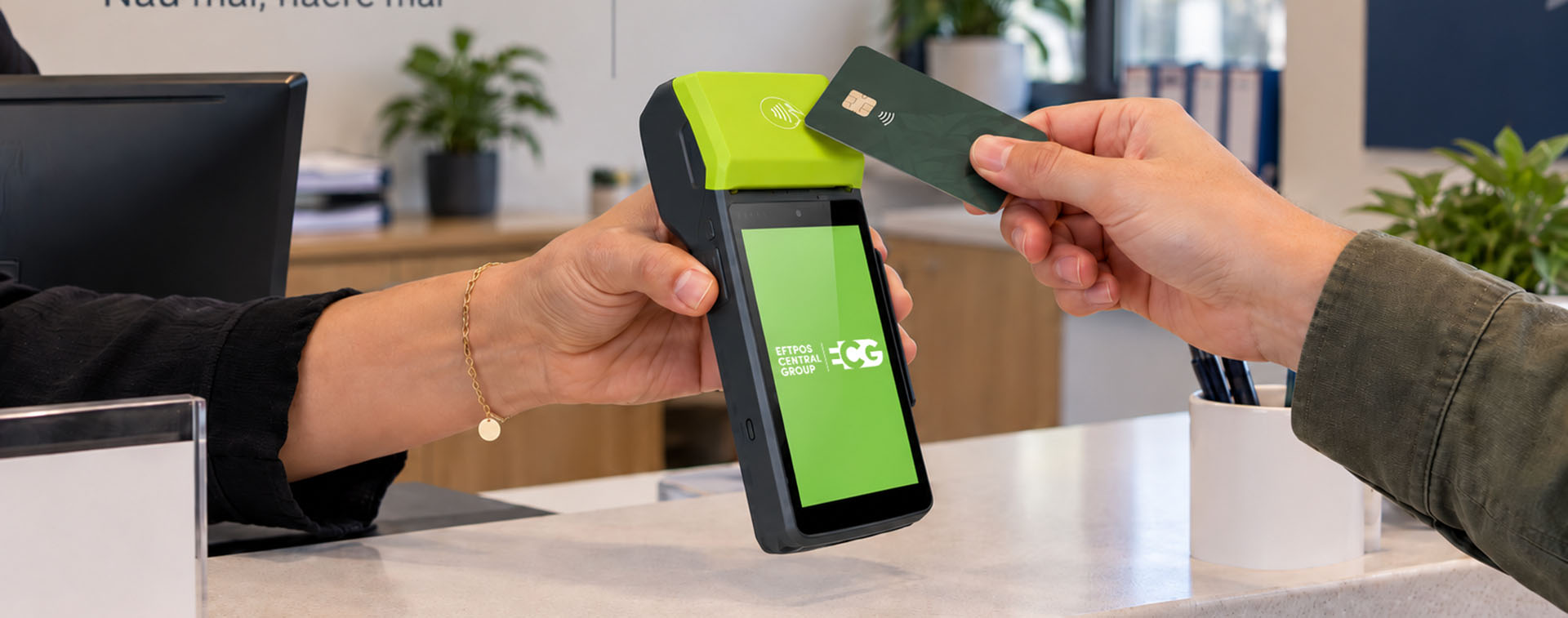 Office Staff using a terminal to take payment from a parent