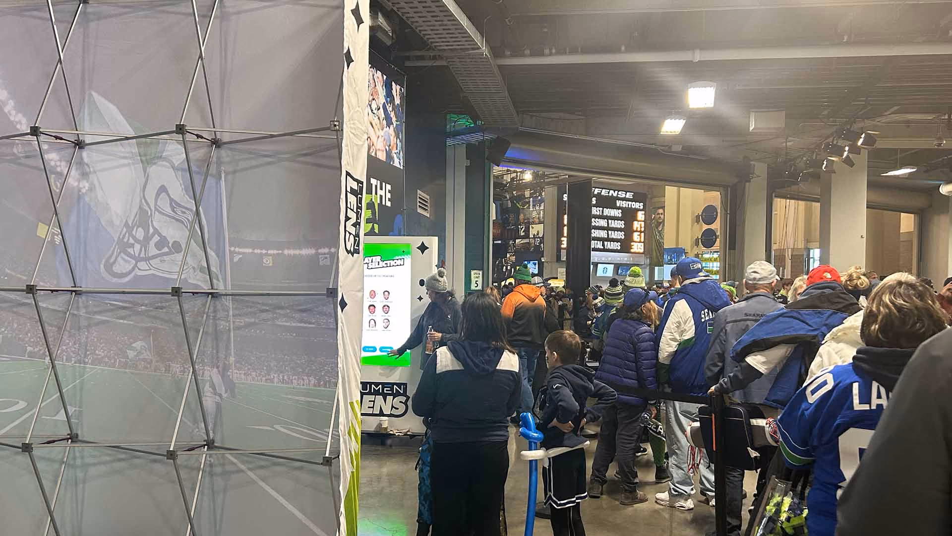A large crowd near a Lumen Lens kiosk, controlled using crowd control barriers.