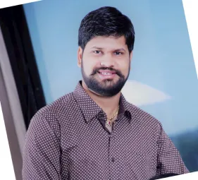 Man with beard smiling, wearing a patterned shirt, with a blue and black background.