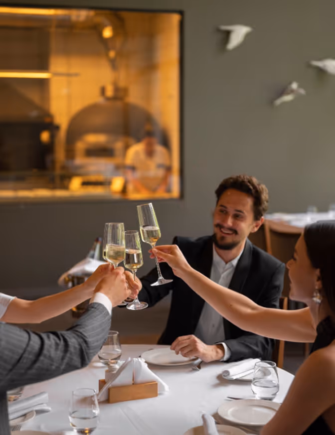 Mehrere Personen stoßen mit Sektgläsern miteinander bei einem Essen an.