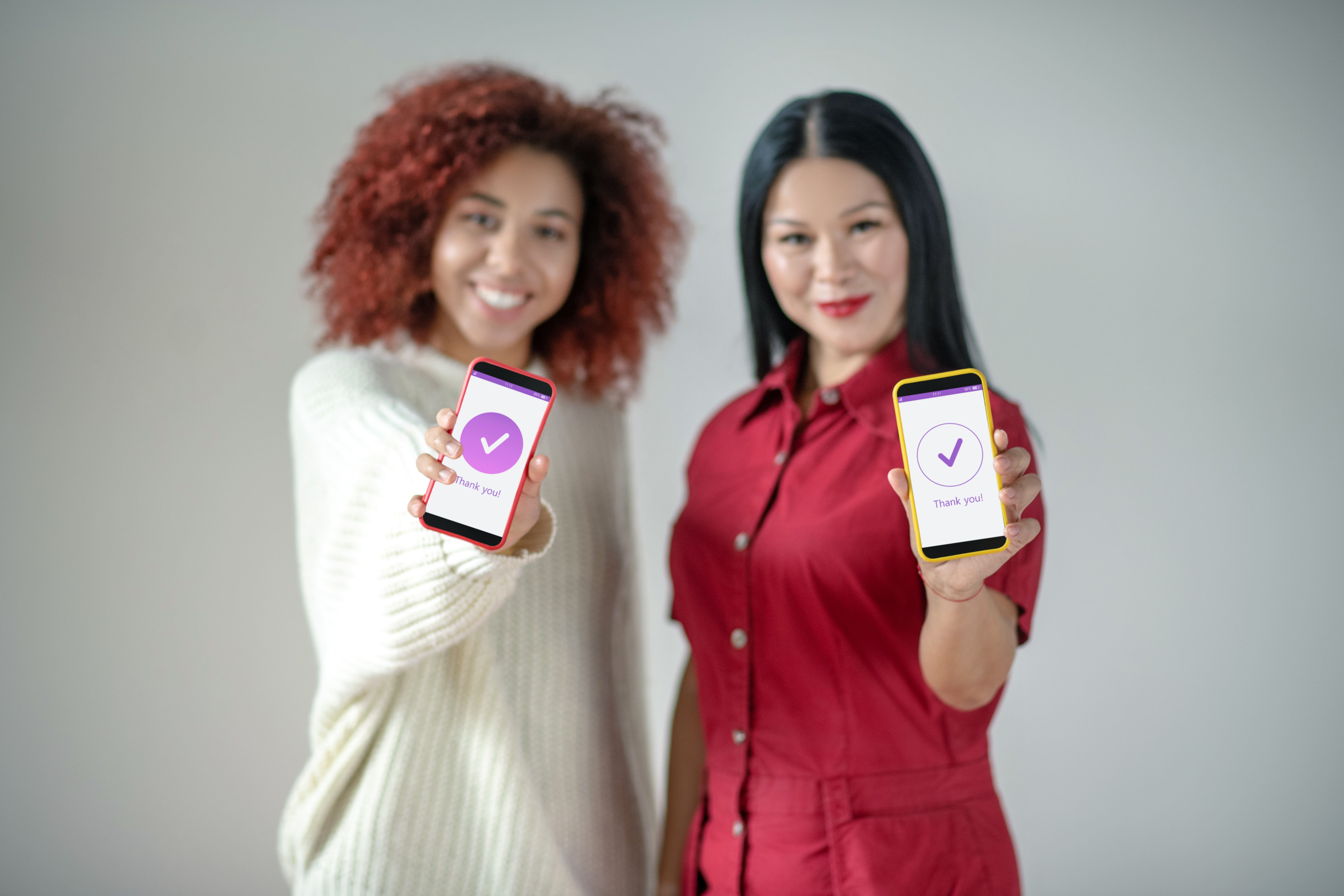 Zwei Frauen halten Handy in der Hand und zeigen App in die Kamera