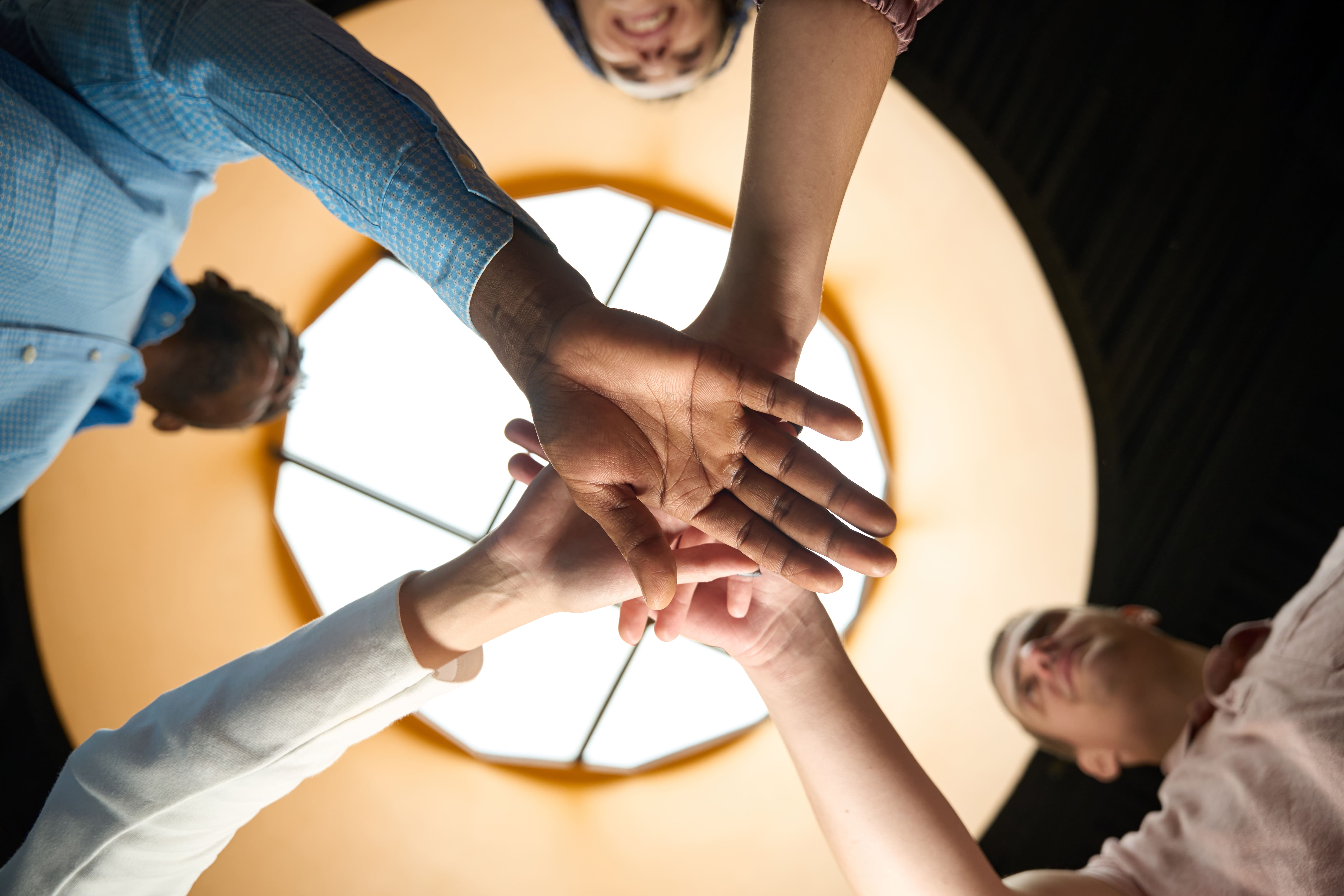 Engagiertes Team, das die Hände zusammenlegt als Symbol für ein freundliches Team