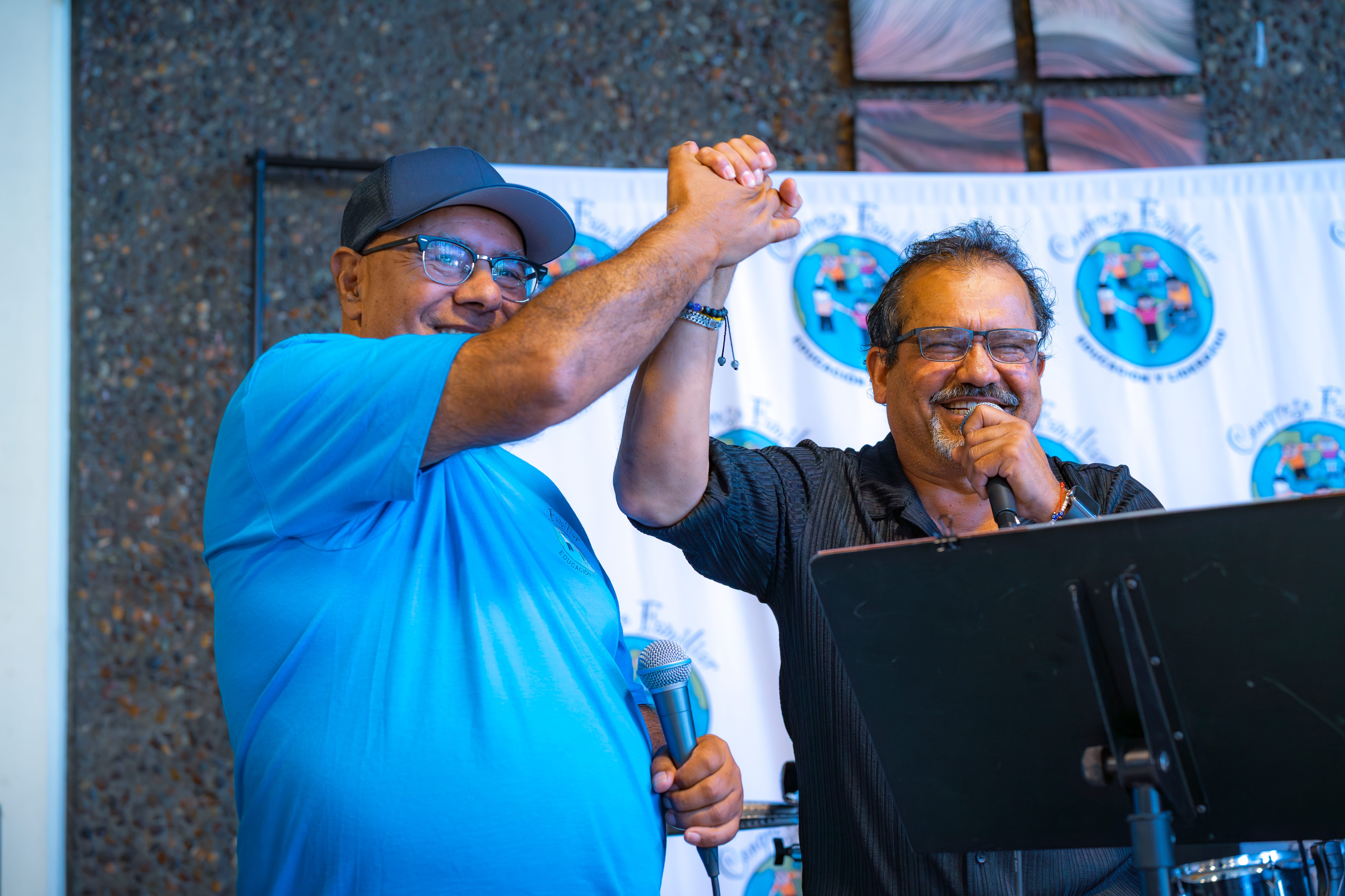 2 men clasping hands with happy expressions. Congresso Familiar 2025.