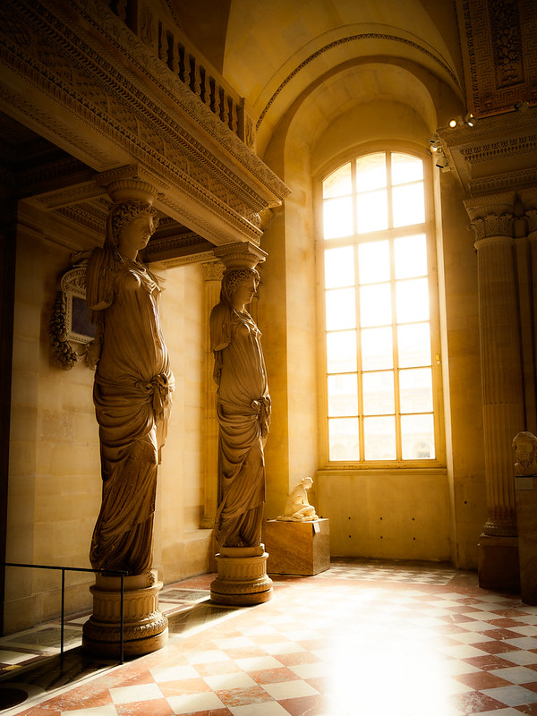 2 statues lit by a blinding sepia window. The floor is white and red checkerboard.