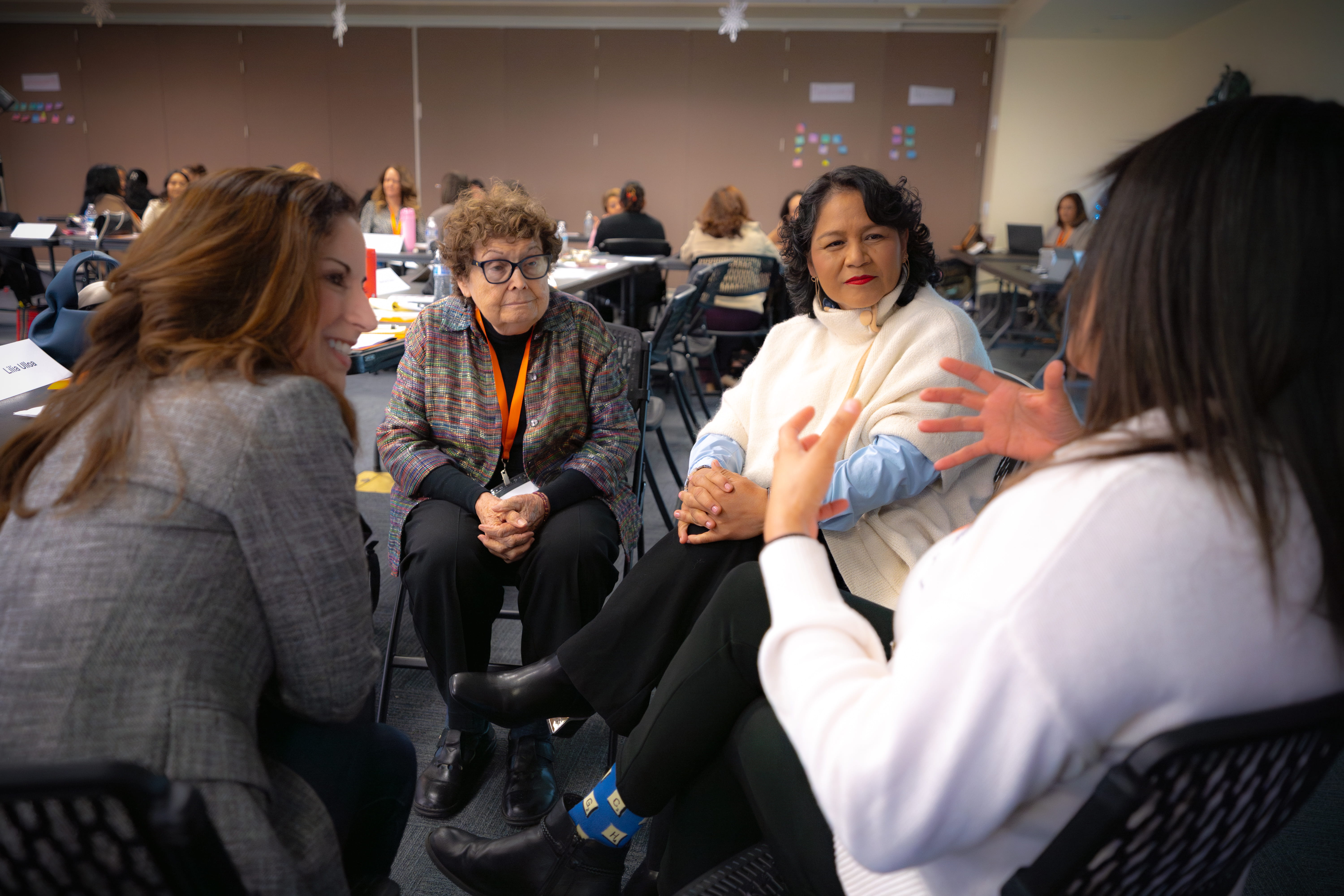 Four people seated in a discussion circle during a workshop in a conference room.