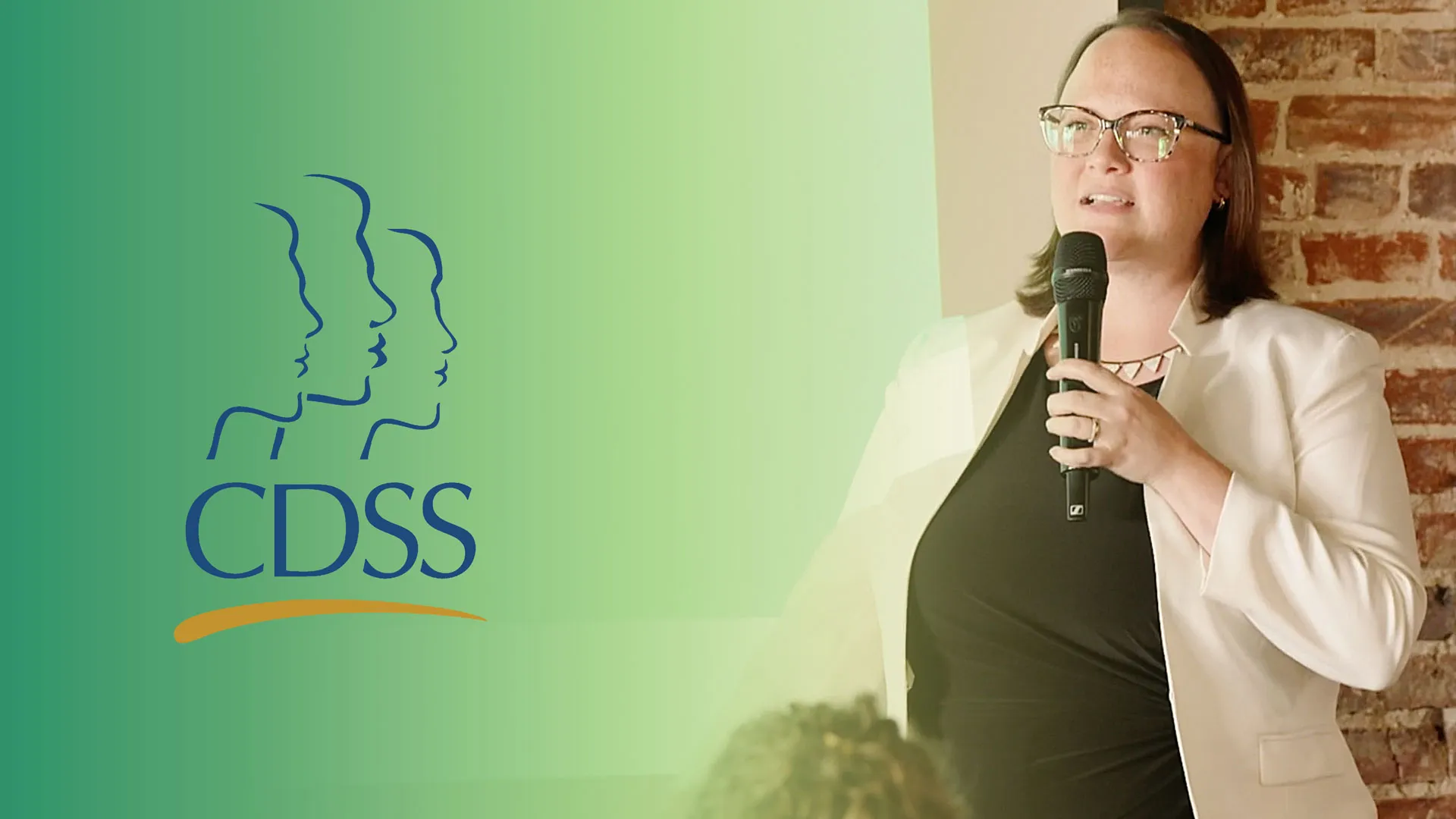 A speaker from CDSS holding a microphone talking to a crowd