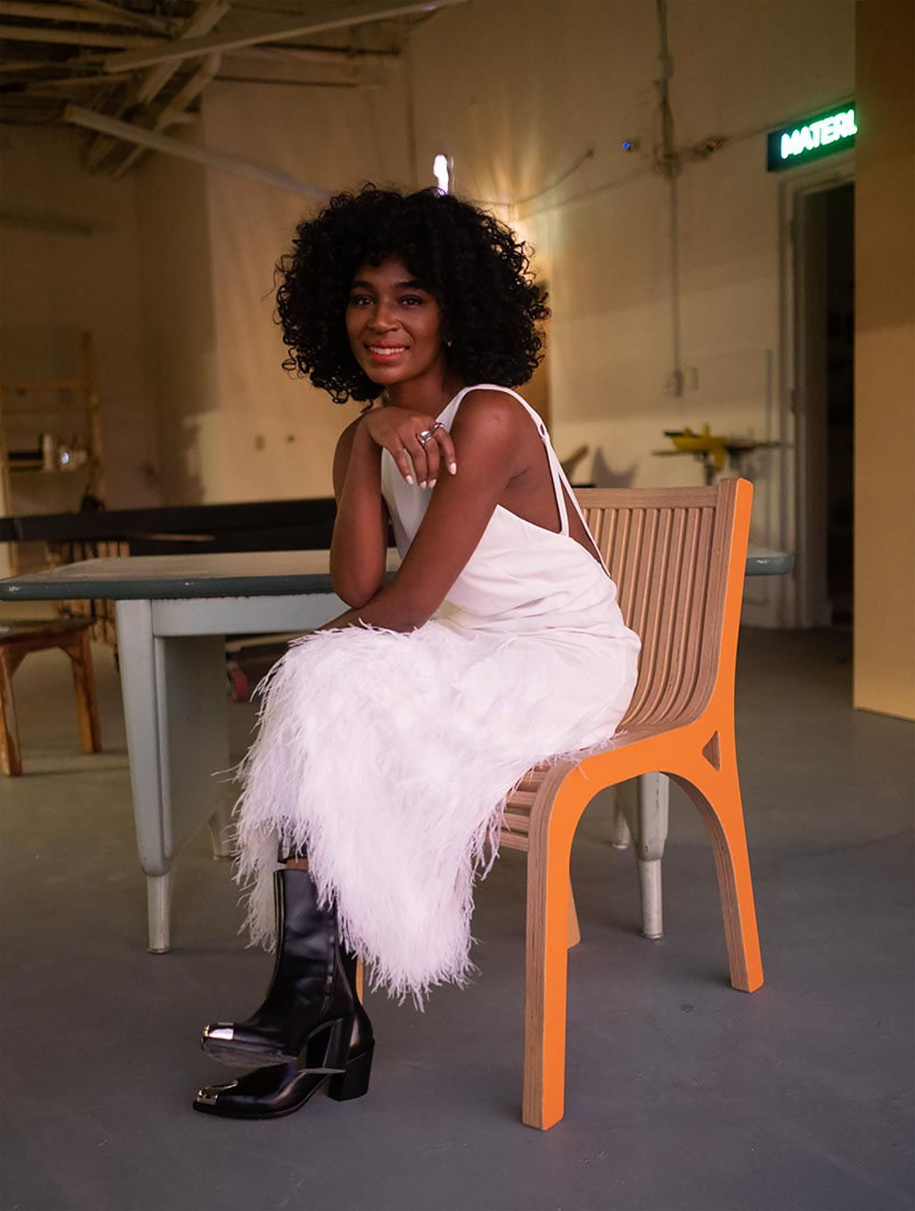 Photograph of Wilden Oche's founder seated and wearing a white dress with boots