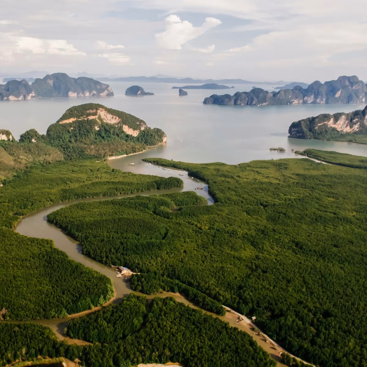 Deux véhicules tout-terrain orange conduisant sur un terrain désertique avec des montagnes et un ciel nuageux en arrière-plan.