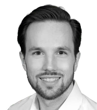 Porträt eines lächelnden Mannes mit kurzem Haar und Bart vor transparentem Hintergrund.