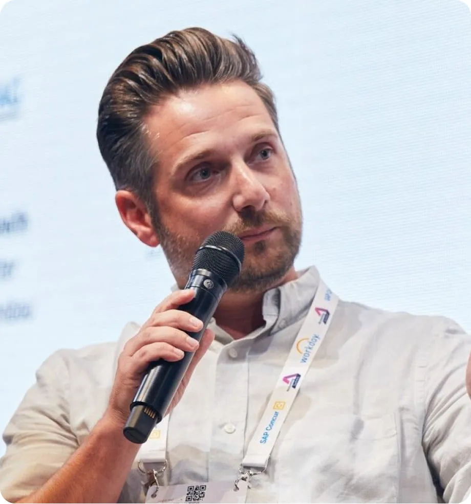 Mann mit Mikrofon in der Hand spricht konzentriert bei einer Veranstaltung.