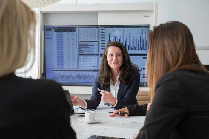 Drei Frauen besprechen Daten und Graphen während eines Meetings in einem modernen Büro.