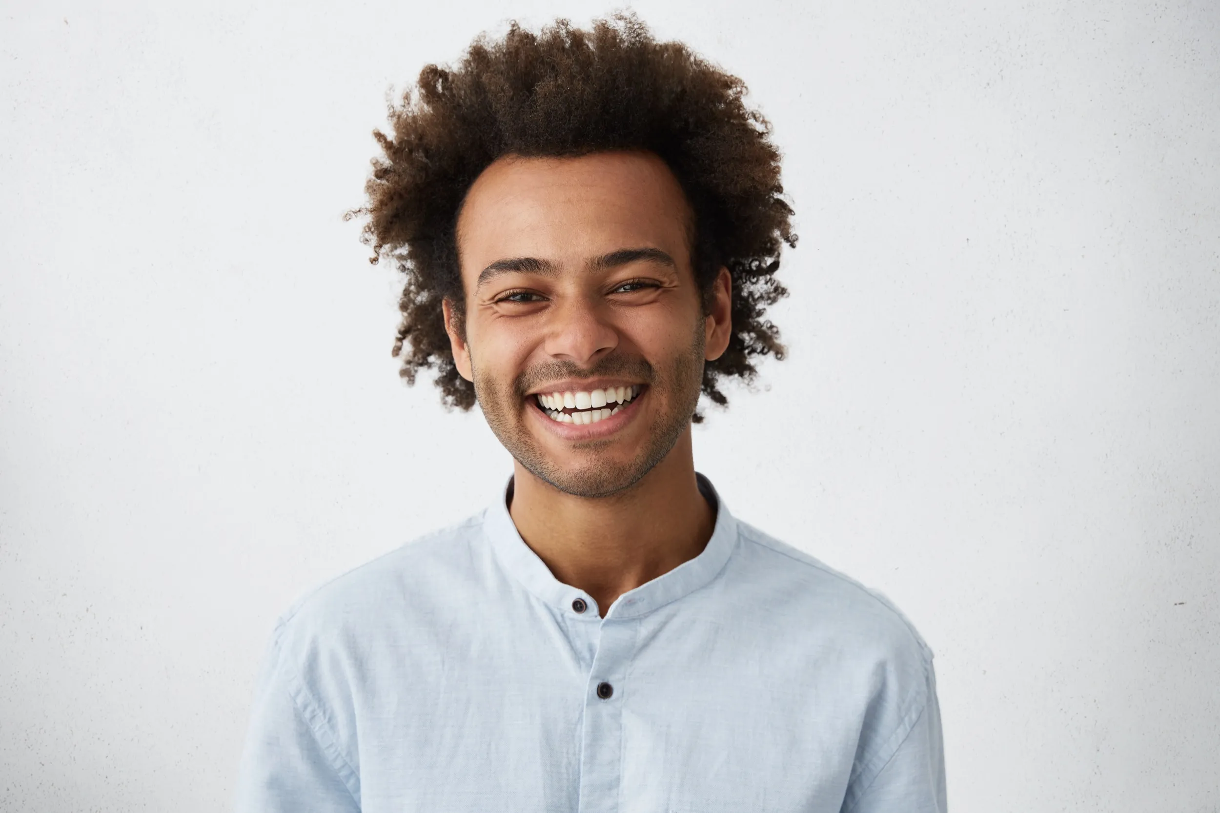 A man with curly hair smiling at the camera