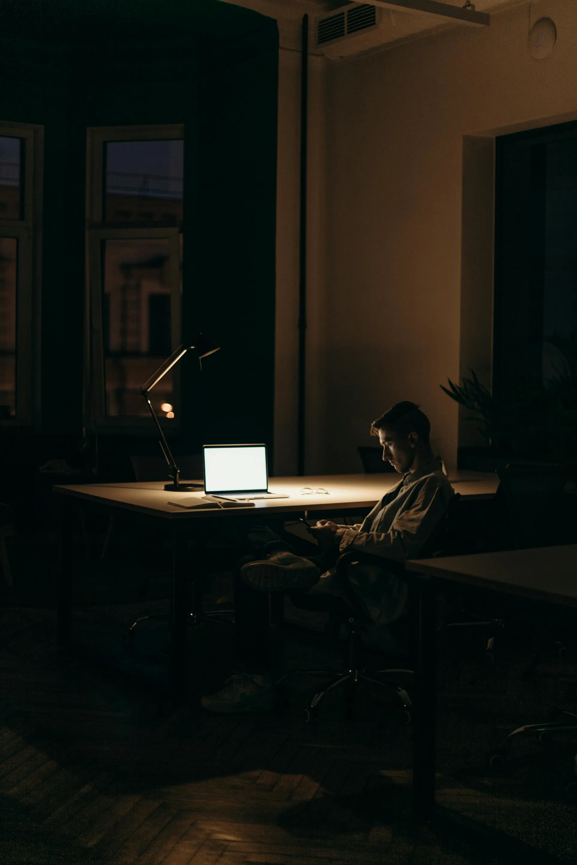 A man sitting at a desk in front of a laptop computer.
