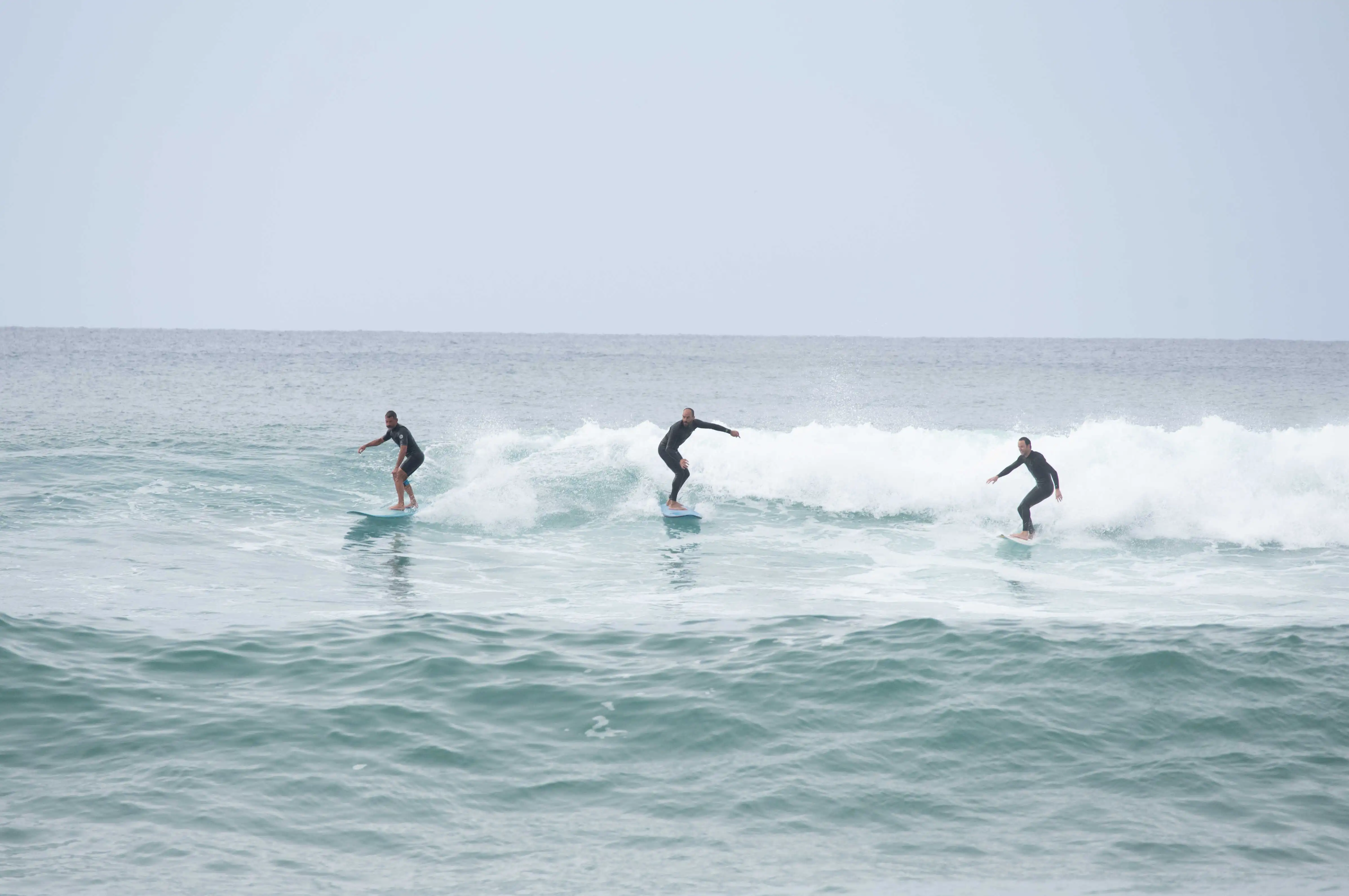 3 surfeurs sur une vague