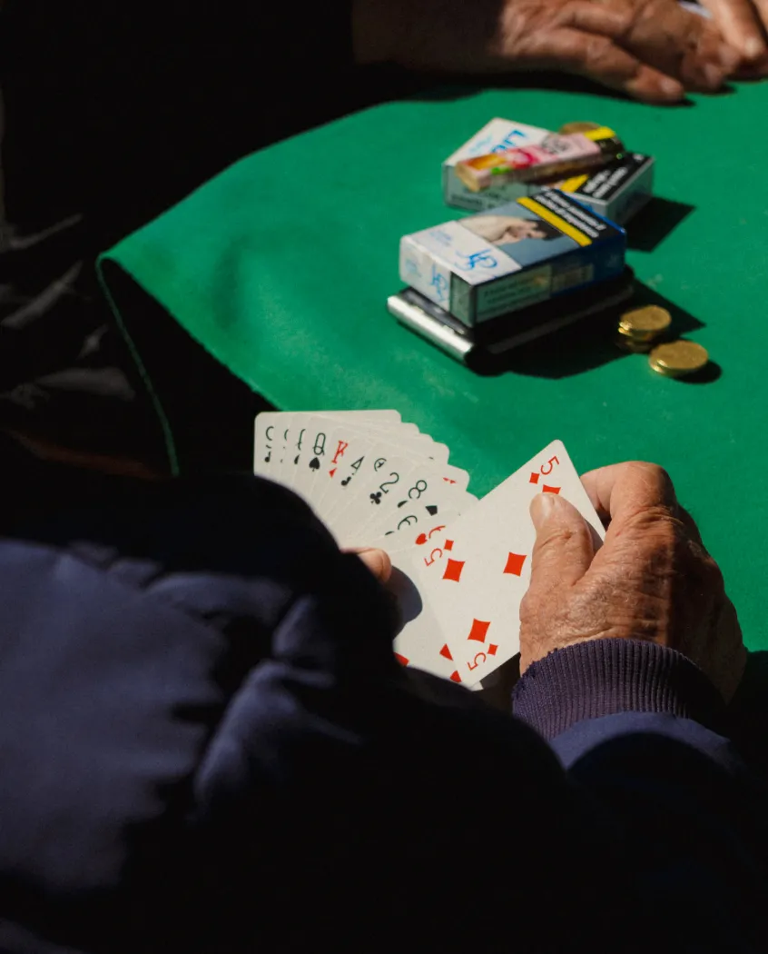 Young woman wearing a knitted hat with a pom-pom and a blue jacket, outdoors near rocky terrain at dusk.