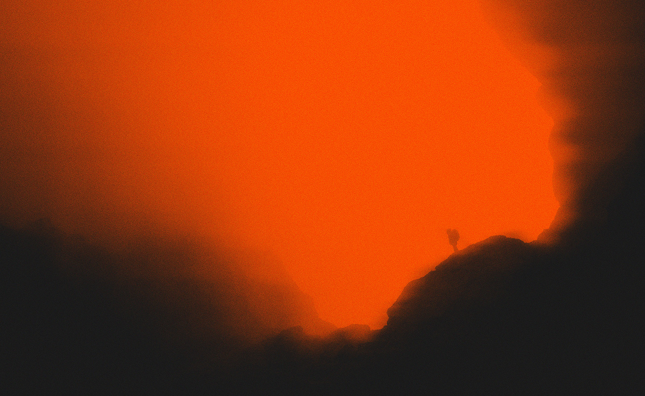 Motorcycle riding on a dirt road winding through a rocky desert canyon landscape.