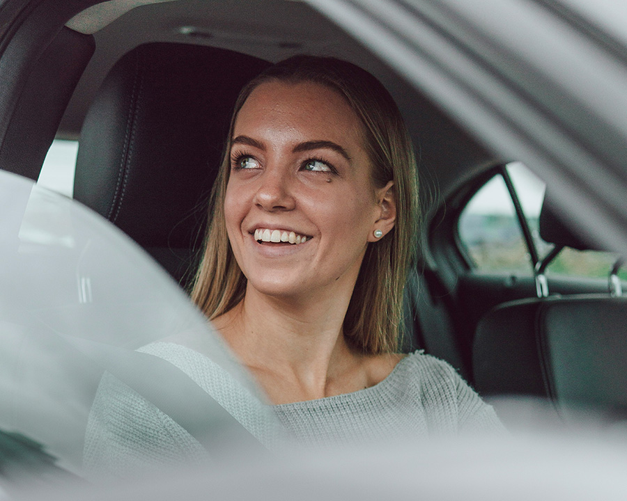 Lachende vrouw achter het stuur van een auto, Drive Strong