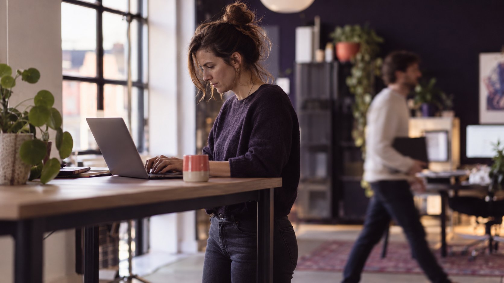 Marketeer werkt staand aan een laptop in een lichte studio