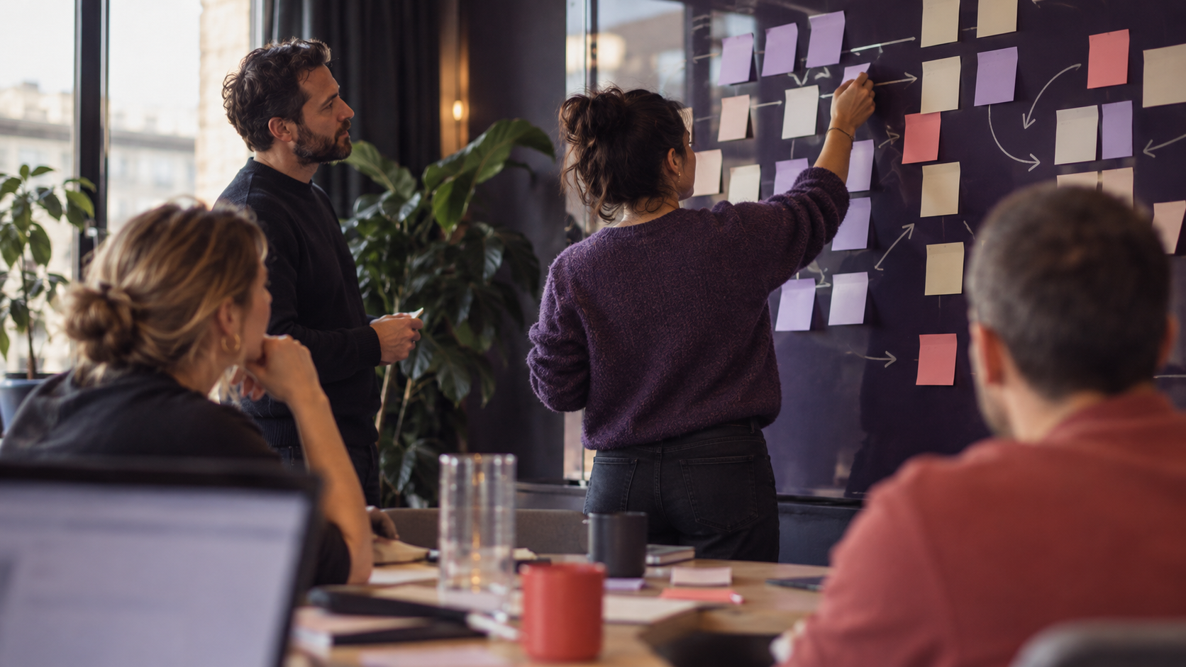 Medewerker ordent post-its met een processchema op een wand