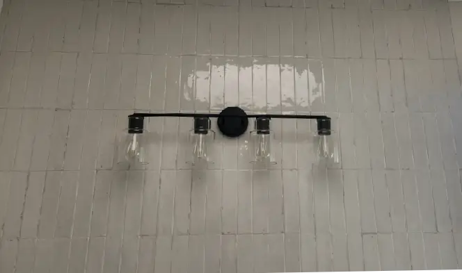 Modern bathroom vanity light fixture installed above tiled wall, showcasing professional electrical installation services in Albuquerque