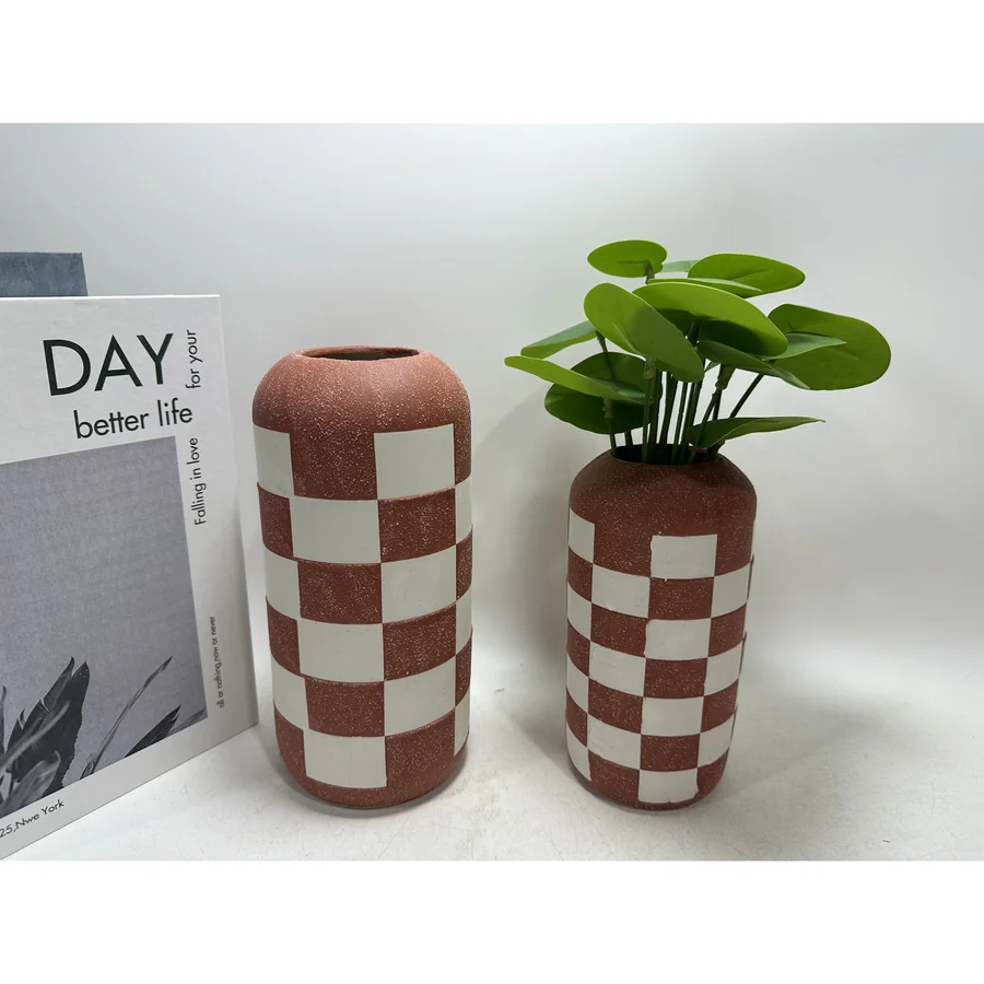 Checkered ceramic vase with green plant.