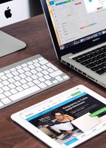 Clavier, tablette avec site web et ordinateur portable MacBook Pro sur un bureau en bois.