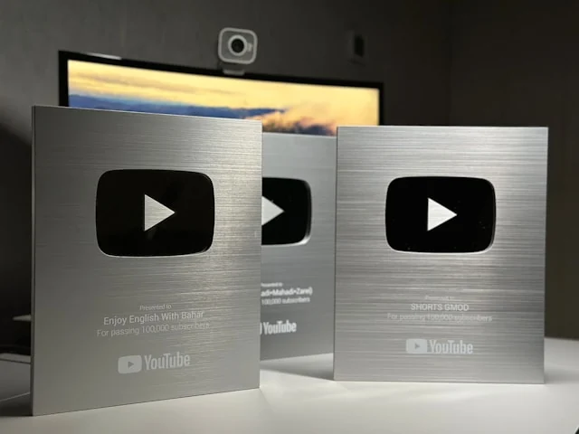 Three YouTube creator award plaques displayed on a desk.