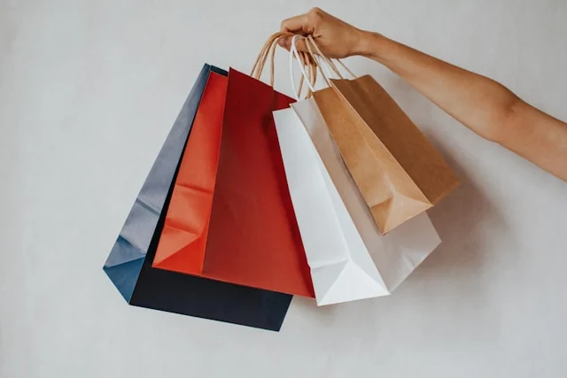 A hand holding several paper shopping bags.