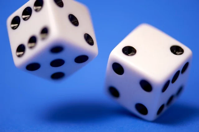 Two white dice suspended above a blue surface.