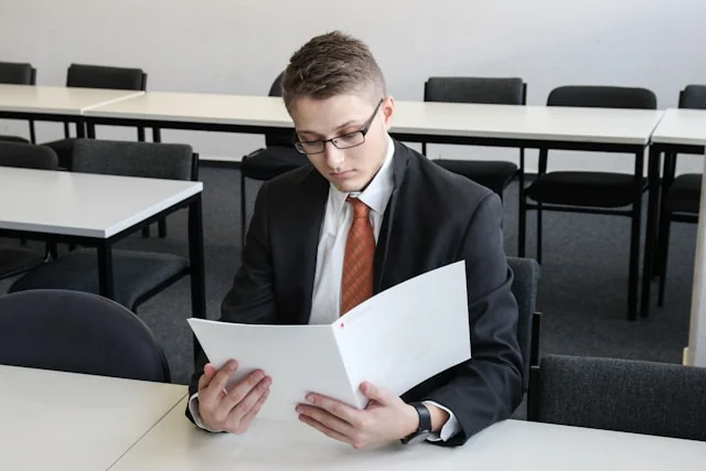 A man in a suit reviewing documents at a table.