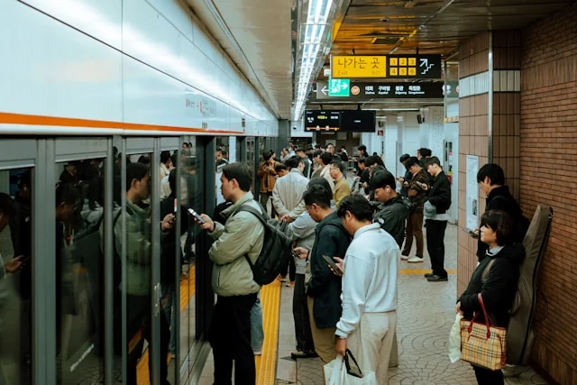 Passengers waiting beside platform screen doors at a busy subway station. Photo by rawkkim on Unsplash