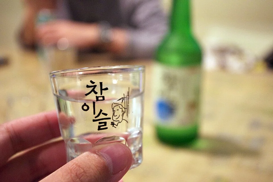 A hand holding a soju shot glass. Image credit: Wikimedia