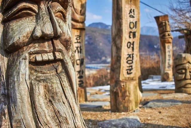 Carved wooden jangseung guardian posts with expressive faces and Korean inscriptions. Photo by Mathew Schwartz on Unsplash