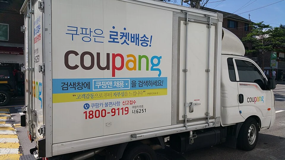 A Coupang delivery truck parked on a Korean street.