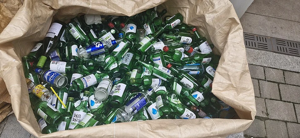 A large sack filled with glass bottles for recycling.