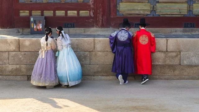 Visitors wearing colourful hanbok outside a traditional Korean building.