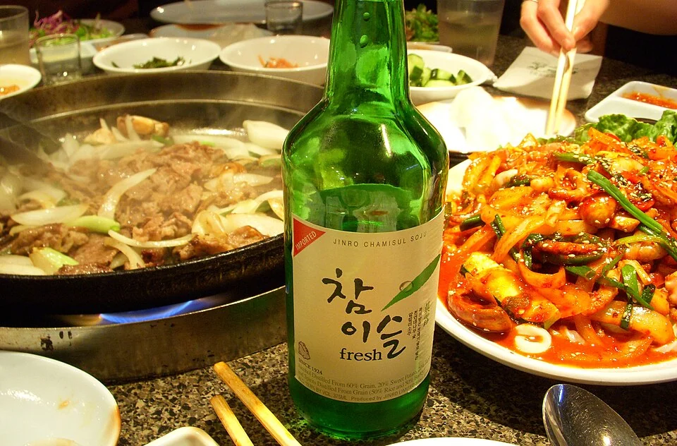 A bottle of soju on a restaurant table with shared dishes.