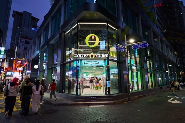 An illuminated Olive Young store on a Korean shopping street at night.