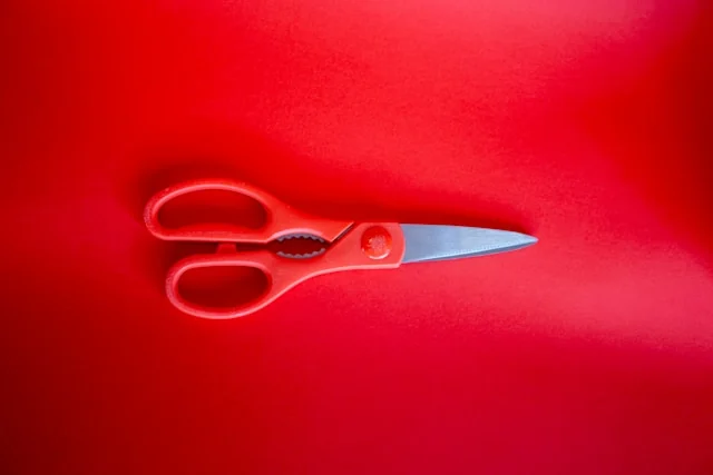 Red kitchen scissors on a red surface.