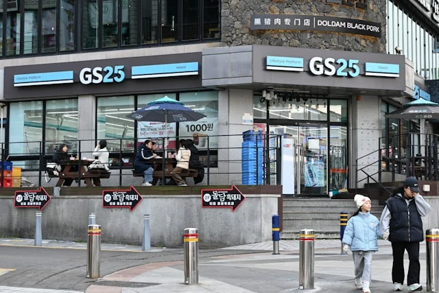 People outside a GS25 convenience store with outdoor seating.
