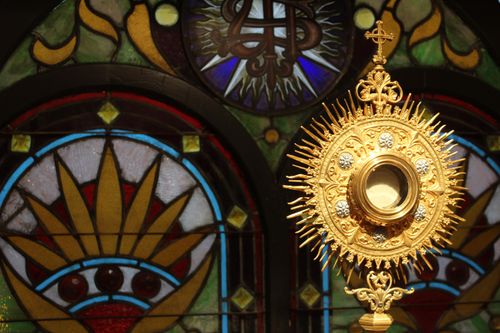 Monstrance in front of stained glass windows